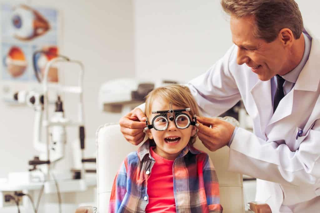 A man optometrist doing an eye test on a little boy