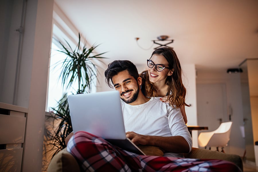 A happy young couple smiling at a laptop