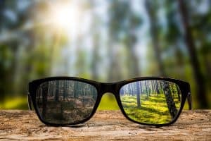 A pair of glasses with a reflection of forest trees in them